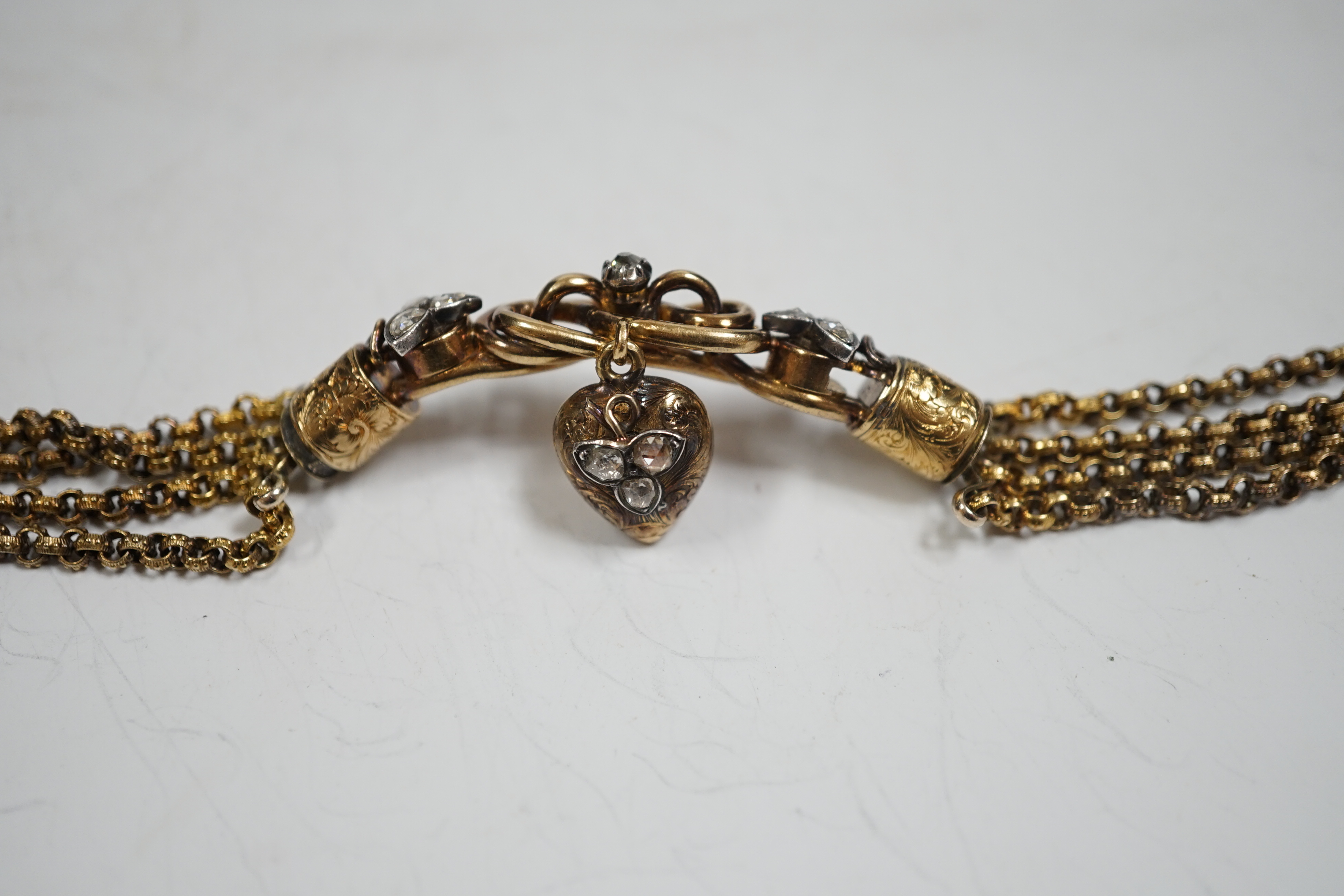 An antique yellow metal (test as 18ct) and rose cut diamond set triple strand bracelet, the central scrolling motif, hung with diamond set heart shaped charm, approx. 17cm, gross weight 30 grams.